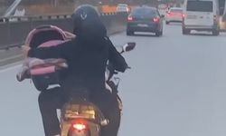 Motosiklet üzerinde bebeği pusetiyle taşıdı